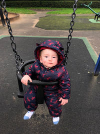 Portrait of cute baby boy swinging in playground