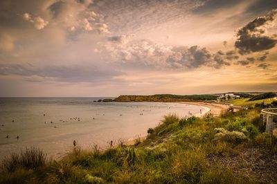 Scenic view of sea against cloudy sky at sunset