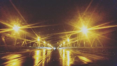 Illuminated road against sky at night