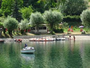 People on riverbank against trees