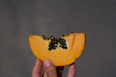 Close-up of hand holding apple against black background