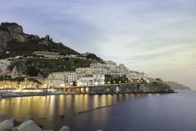 Buildings by sea against sky in city