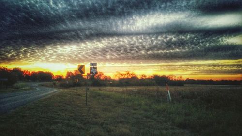 Scenic view of field against cloudy sky at sunset