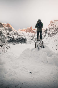 Rear view of man standing on snow covered land against mountains