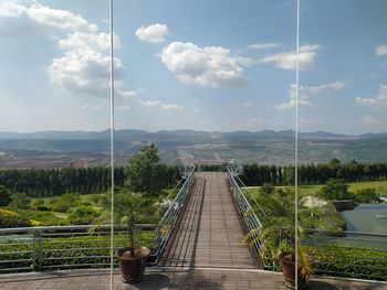 Boardwalk leading towards mountain against sky