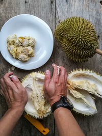 High angle view of man opening durian on table