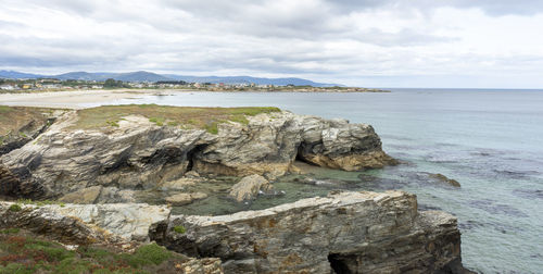 Scenic view of rocks on shore against sky