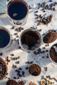 Still life with glass mugs of black hot coffee, coffee beans, ground coffee, making coffee at home