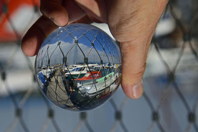 Cropped hand holding crystal ball at harbor