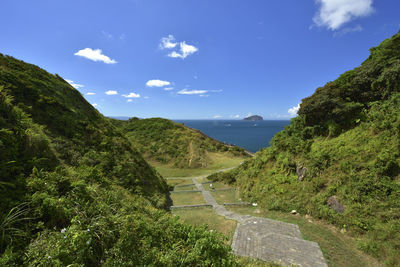 Scenic view of mountains by sea against blue sky