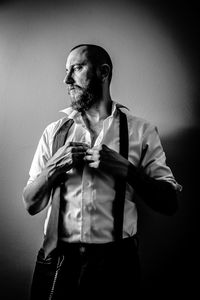 Young man looking away while standing against wall