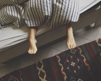 Low section of woman relaxing on bed at home