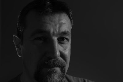 Close-up portrait of mature man against black background