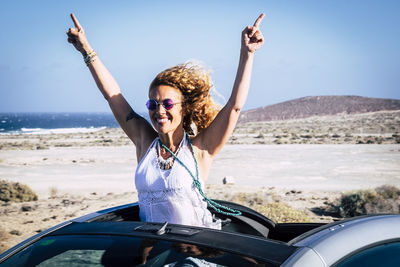 Smiling woman pointing in car against clear sky