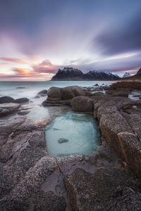 Scenic view of rocks and sea against sky during sunset