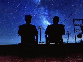 Silhouette men standing against clear sky at night