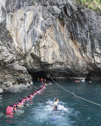 People on rock formation in water