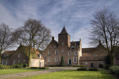 Houses by trees and buildings against sky