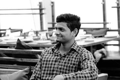 Smiling young man looking away while sitting at cafe