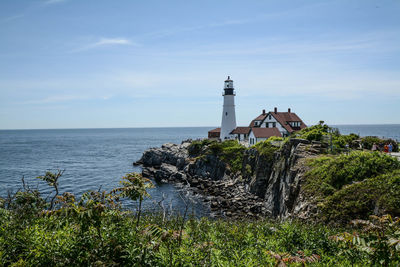 Lighthouse by sea against sky