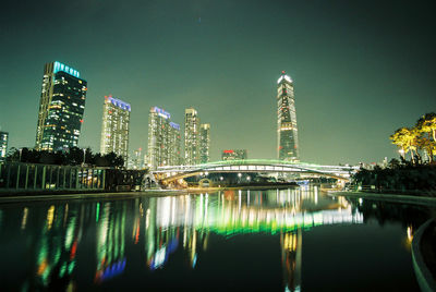 Illuminated modern buildings in city against sky at night