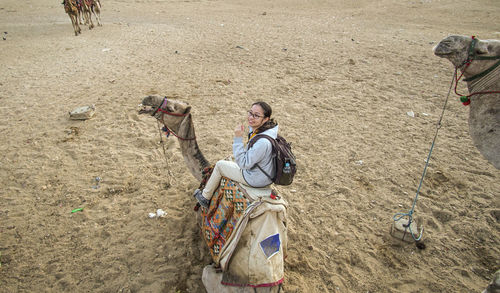 Asian woman tourist having fun exciting camel riding to see pyramid tour