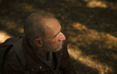 Portrait of adult man in forest in autumn with sunlight and shadow