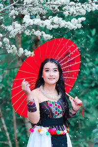 Portrait of a smiling young woman standing against wall