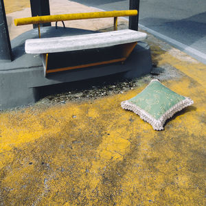 High angle view of abandoned cushion by bench on footpath