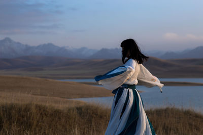 Rear view of woman standing on mountain against sky