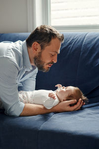 Proud caucasian father talking to newborn baby girl. smiling happy parent man calming down child