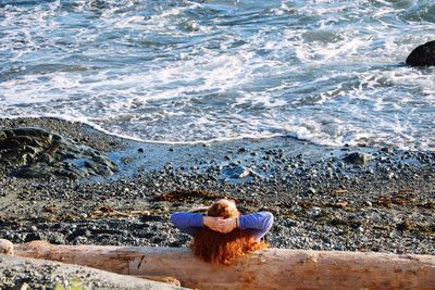 Rear view of woman sitting on beach