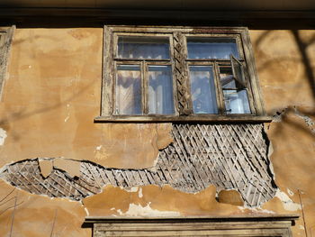 Low angle view of broken glass window in abandoned building