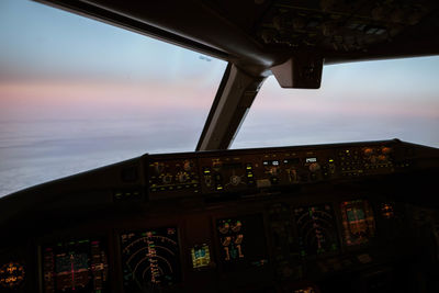 Airplane window against sky during sunset