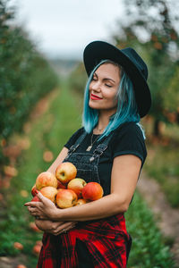 Young woman holding strawberry while standing outdoors