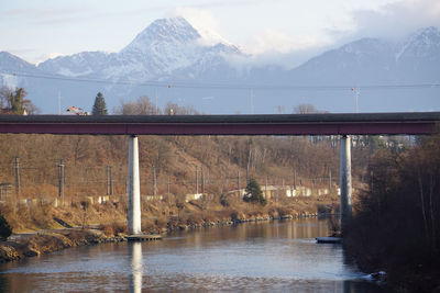 Bridge over lake by mountains against sky
