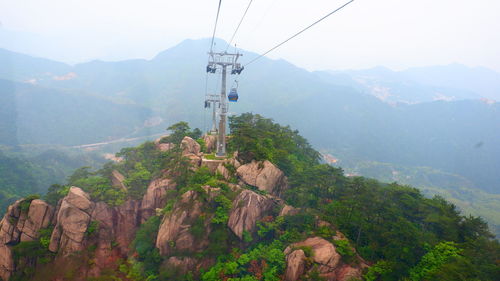 Overhead cable car over mountains against sky