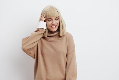 Portrait of young woman standing against white background