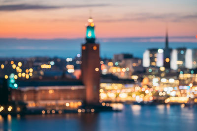 Illuminated buildings at waterfront during sunset