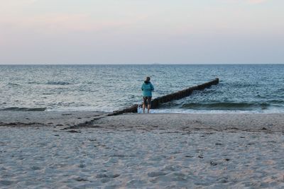 Man standing on beach against sky during sunset