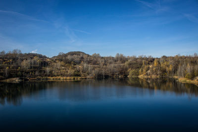 Scenic view of lake by trees against blue sky