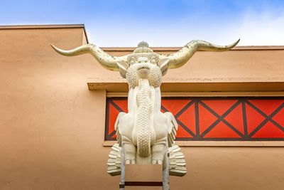 Low angle view of statue against building against sky