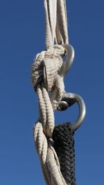 Close-up of rope tied up against blue sky