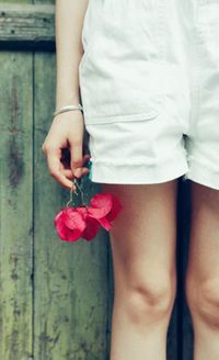 Midsection of woman standing by red rose