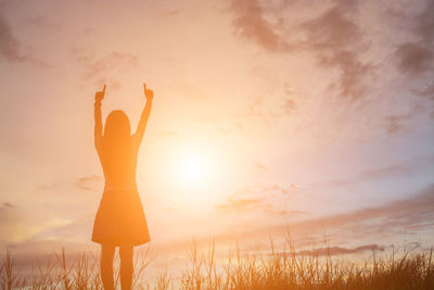 Low section of woman standing on field against sky during sunset