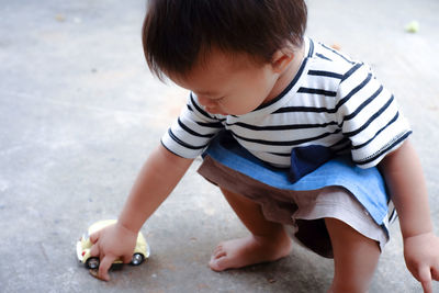 Cute boy playing with toy car on footpath