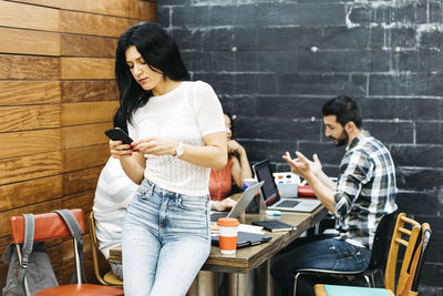 Young woman using mobile phone while sitting on floor