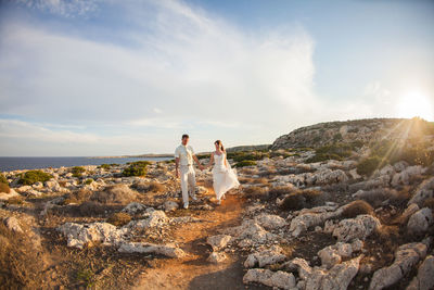 People standing on rock against sky