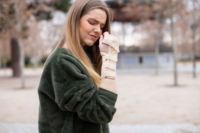 Young woman with fractured hand standing on street