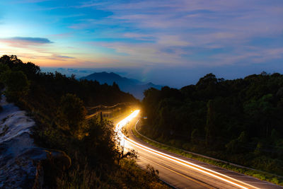 Light trails on road against sky at sunset